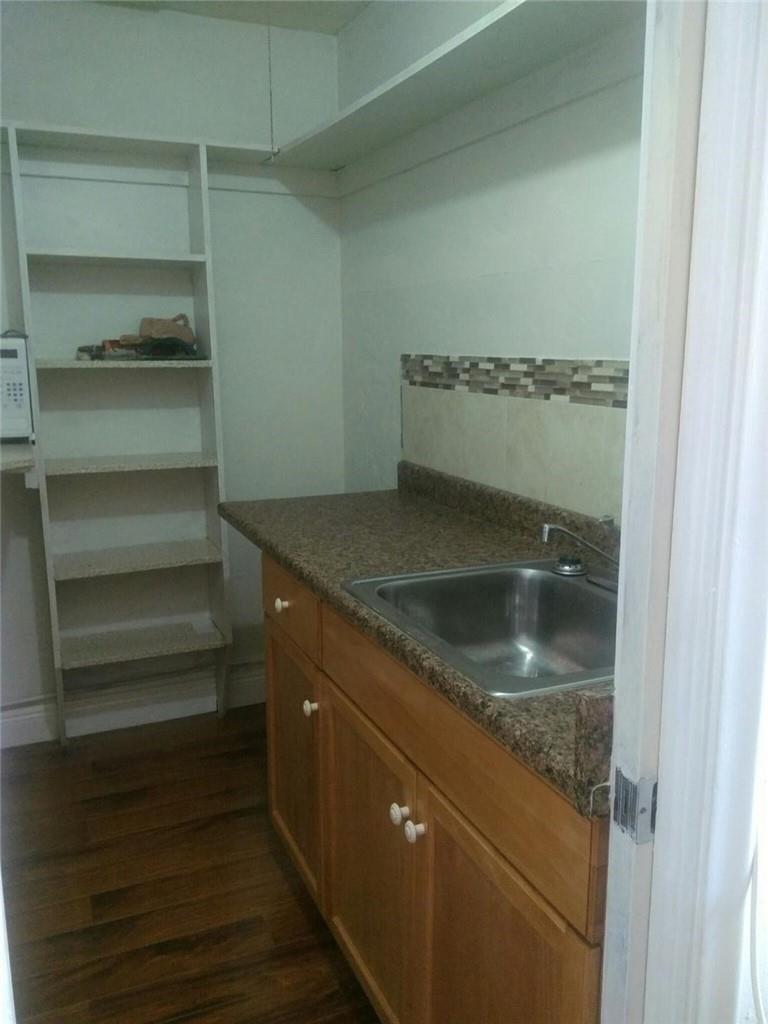 A small kitchenette features a stainless steel sink, wood cabinets, and open shelving — 6764 AZALEA Drive, Miramar FL 33023, MIRAMAR, FL