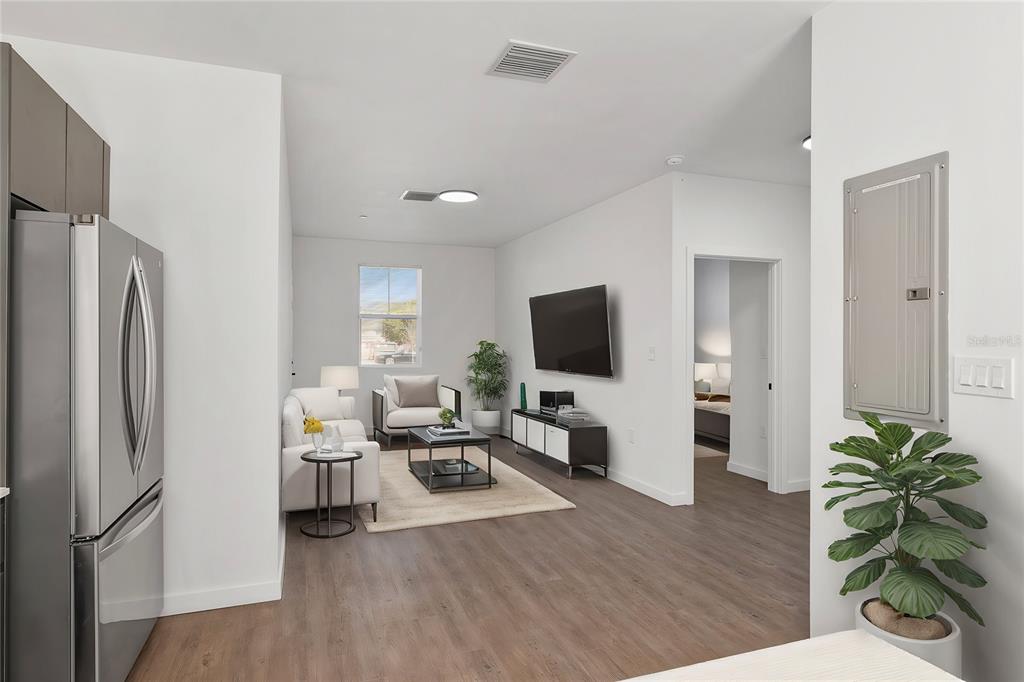 A modern living room with wood-look flooring, a wall-mounted television, and an adjacent kitchen area — 1581 NW 29TH ROAD UNIT 2, GAINESVILLE, FL
