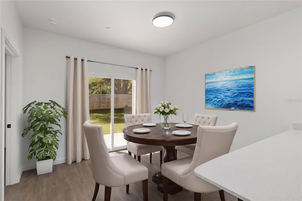 A dining room features a round wooden table, upholstered chairs, and a sliding glass door — 1581 NW 29TH ROAD UNIT 2, GAINESVILLE, FL