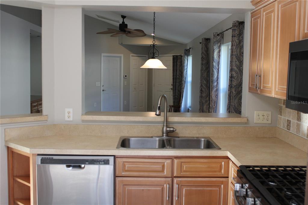 A kitchen features light wood cabinets, a stainless steel dishwasher, and a double-basin sink — 3931 DAY BRIDGE PLACE, ELLENTON, FL