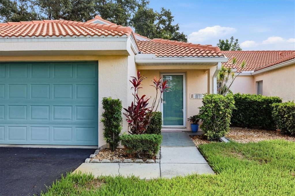 A single-story home with a teal garage door, a front entrance, and a tiled roof — 608 TYSON TERRACE UNIT 8, VENICE, FL
