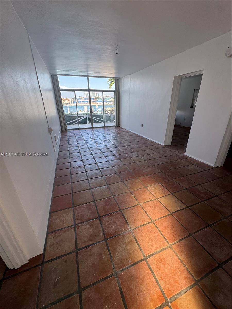 An empty room features terracotta tile flooring, white walls, and large sliding glass doors — 10281 E Bay Harbor Dr # C2, Bay Harbor Islands FL 33154, BAY HARBOR ISLANDS, FL