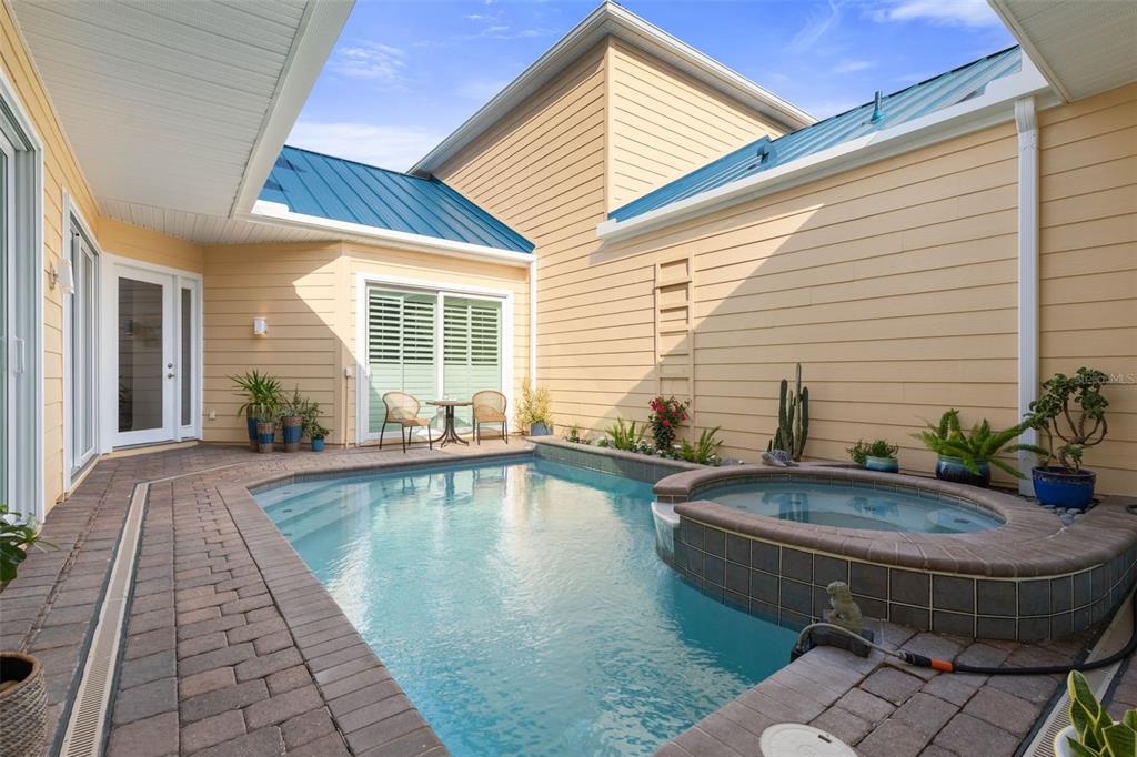 A courtyard features a swimming pool and attached hot tub surrounded by tan siding walls — 4642 RIVERWALK VILLAGE COURT, PONCE INLET, FL