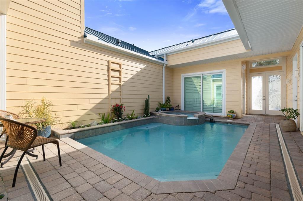 A small rectangular swimming pool and attached hot tub sit in a paved courtyard — 4642 RIVERWALK VILLAGE COURT, PONCE INLET, FL