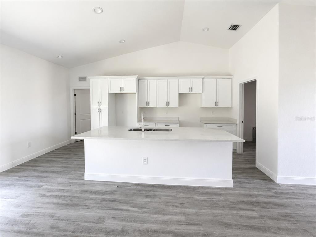 A kitchen with white cabinets, a large island, and light wood-look flooring — 6203 FOREST COURT, LABELLE, FL