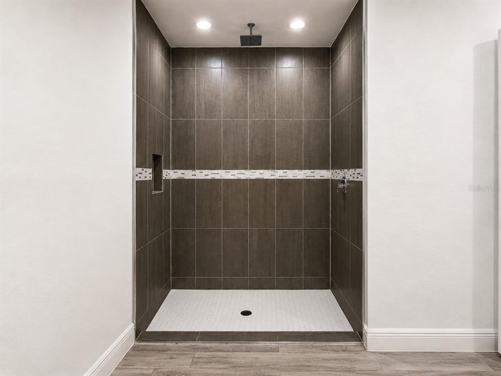A walk-in shower features dark tiled walls, a mosaic accent strip, and a white floor — 6203 FOREST COURT, LABELLE, FL