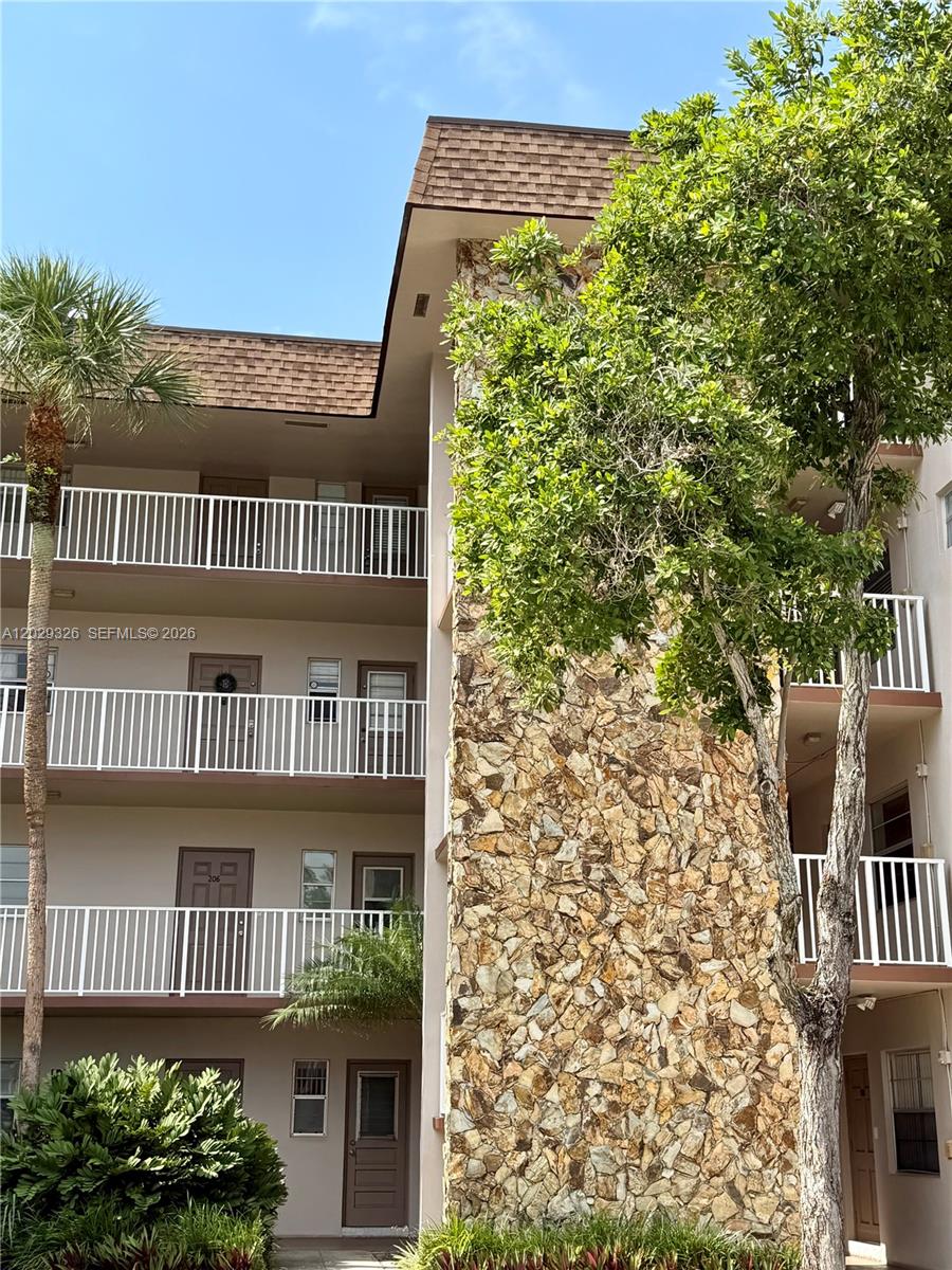 A multi-story apartment building exterior features white railings, brown doors, and a stone-clad wall — 8101 SW 24th Ct # 405, Davie FL 33324, DAVIE, FL