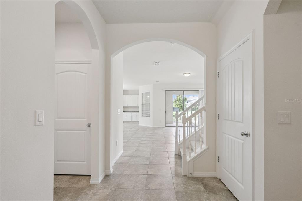 A bright entryway features tiled floors, arched doorways, white doors, and a staircase — 16031 PEBBLE BLUFF LOOP, WINTER GARDEN, FL