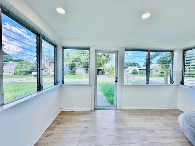 A sunroom with light wood-look flooring, white walls, and multiple louvered windows — 624 ILLINOIS AVENUE, ST CLOUD, FL
