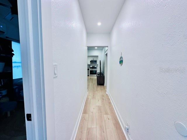 A narrow hallway with light wood-look flooring leads toward a kitchen in the distance — 624 ILLINOIS AVENUE, ST CLOUD, FL
