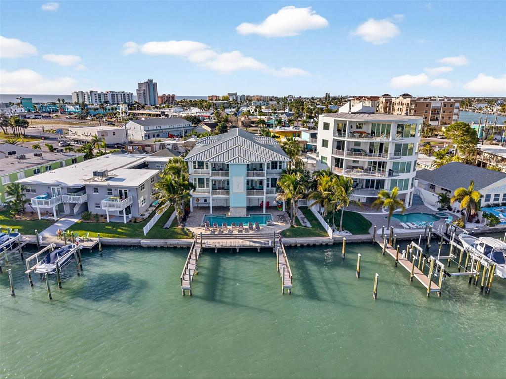 An aerial view shows three waterfront buildings with pools and private boat docks — 255 104TH AVENUE, TREASURE ISLAND, FL