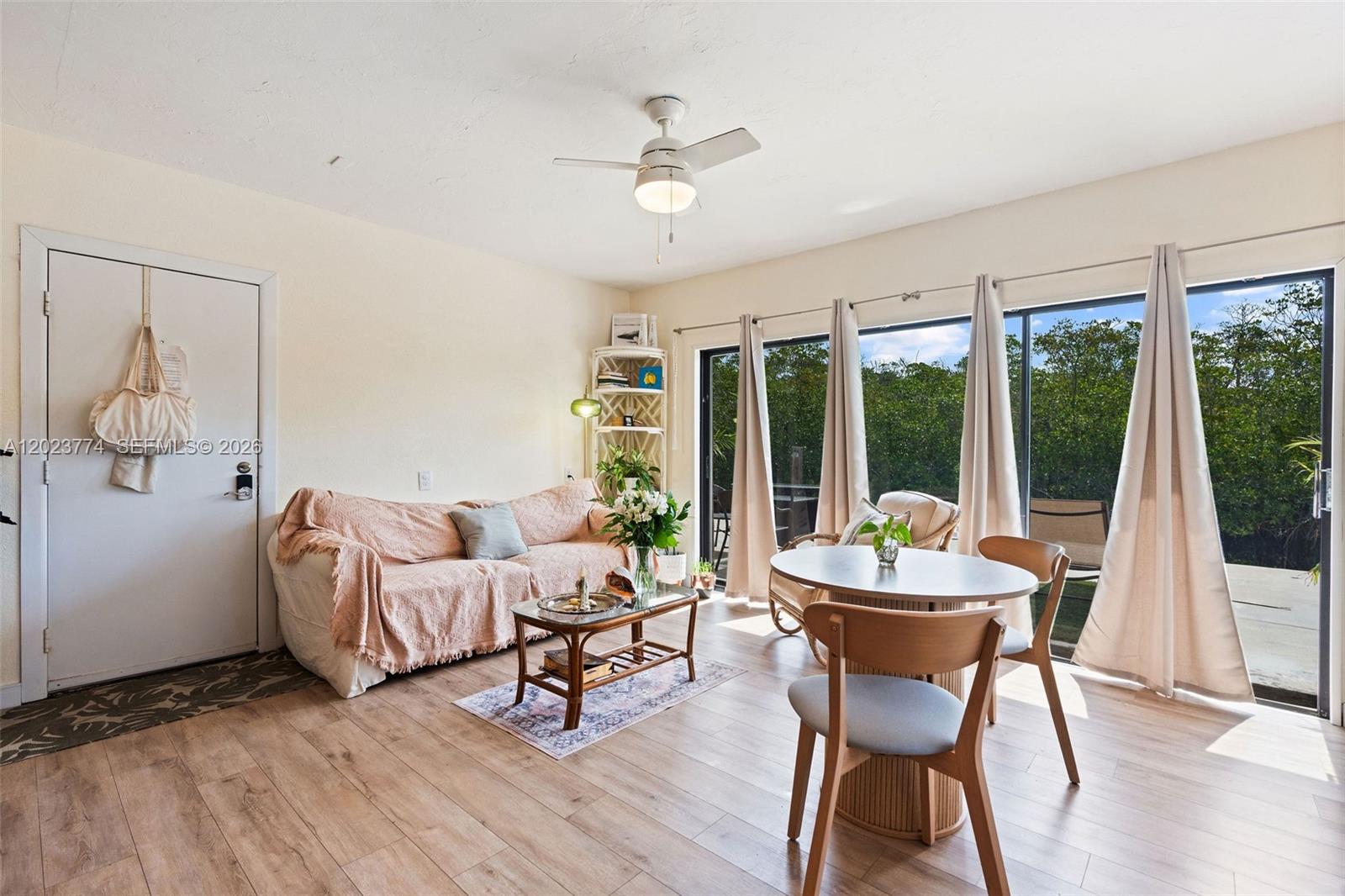 A living room features a sofa, a dining set, and sliding glass doors overlooking trees — KEY LARGO, FL