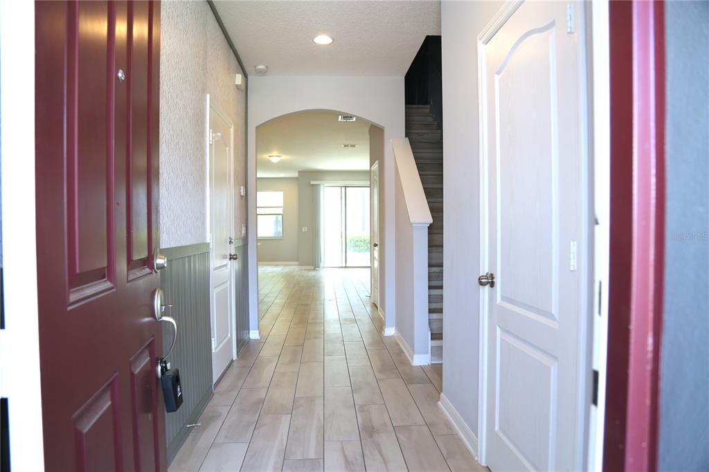 A view from an open front door into a hallway with tile floors and stairs — 229 RUSTIC LOOP, SANFORD, FL