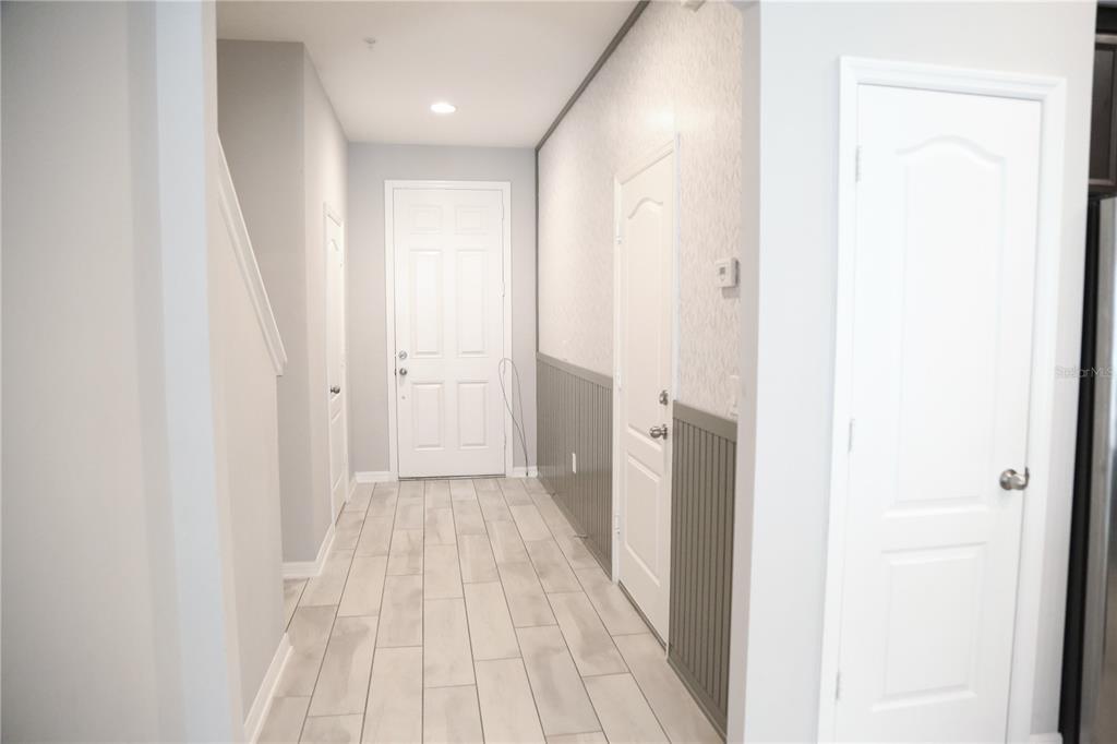 A hallway with light-colored tile flooring, gray wainscoting, and several white interior doors — 229 RUSTIC LOOP, SANFORD, FL