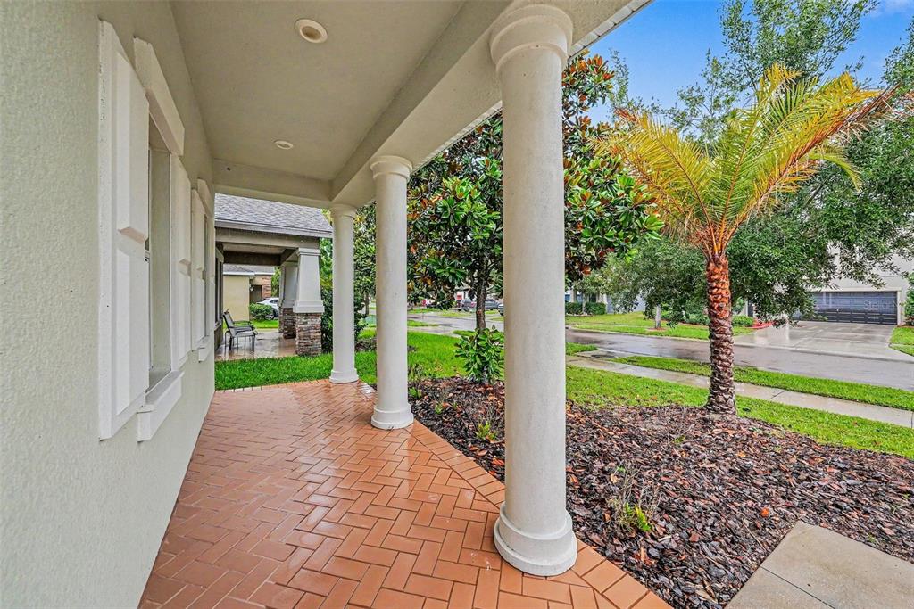 A covered front porch features white columns, a brick-patterned floor, and a view of landscaping — 11809 TWILIGHT DARNER PLACE, RIVERVIEW, FL