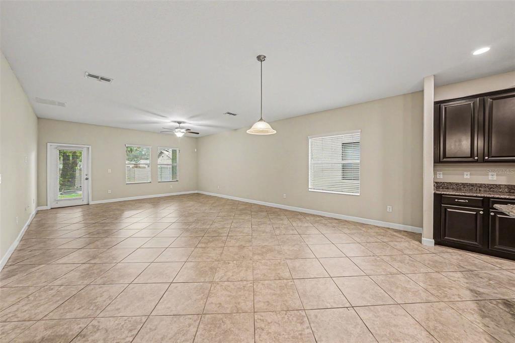 An open-concept living and dining area features beige tile flooring and dark wood kitchen cabinets — 11809 TWILIGHT DARNER PLACE, RIVERVIEW, FL