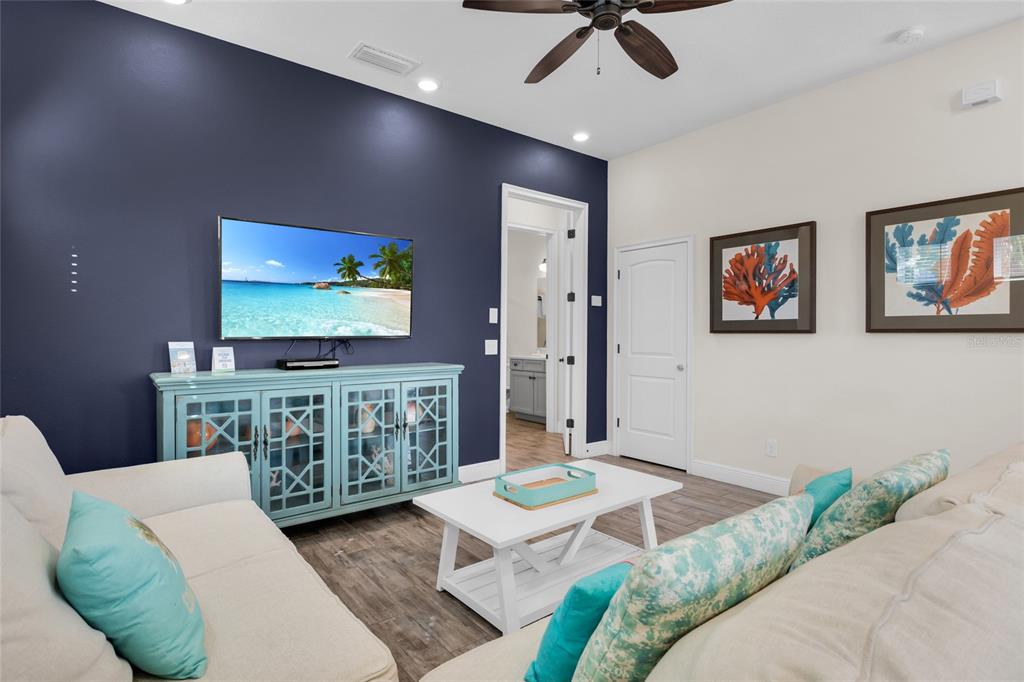 A living room features a dark blue accent wall, a light blue media console, and sofas — 2972 SALTED RIM ROAD, KISSIMMEE, FL