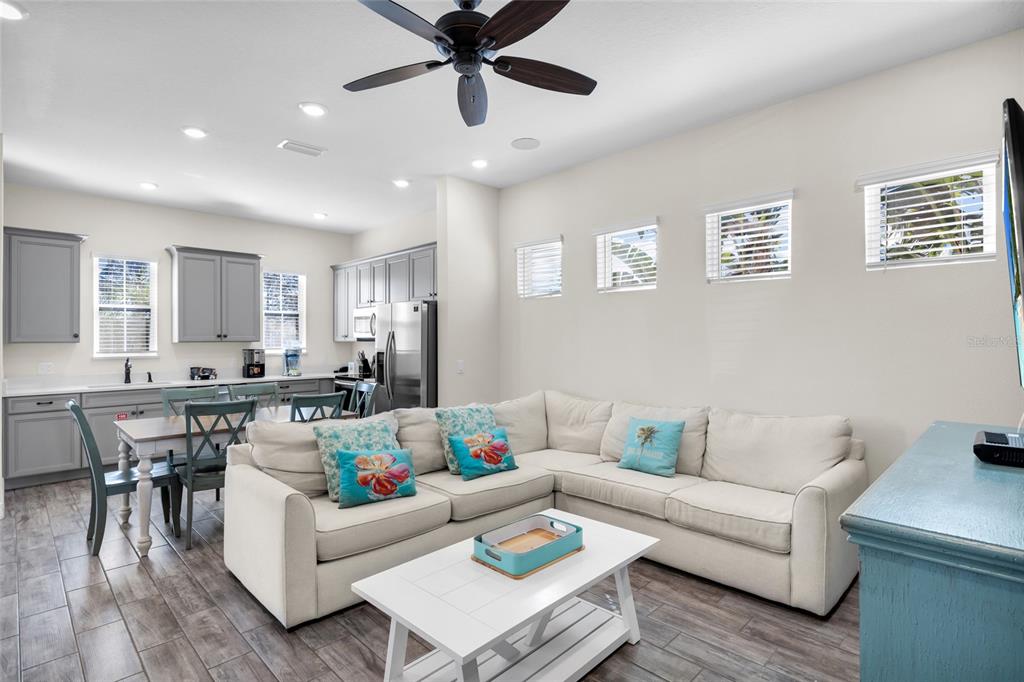 An open-concept living room and kitchen featuring a sectional sofa, dining area, and gray cabinetry — 2972 SALTED RIM ROAD, KISSIMMEE, FL