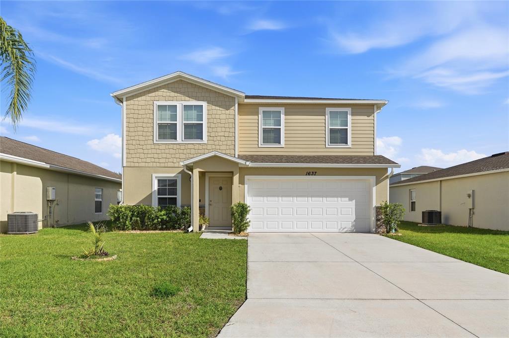 A two-story tan house with a two-car garage and a concrete driveway — 1637 MARBLE STREET, SEBRING, FL