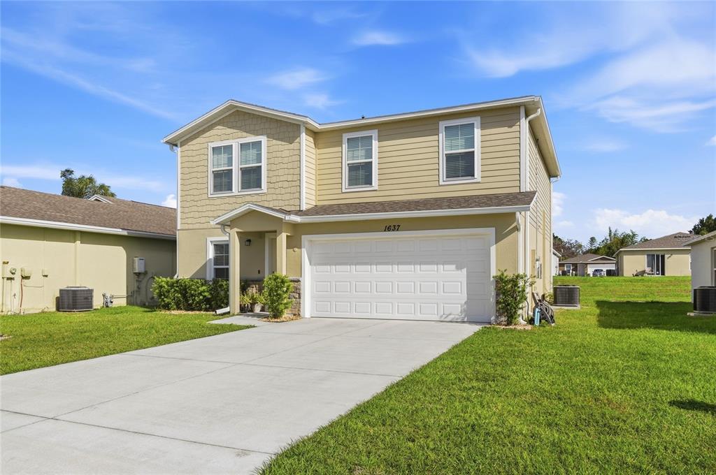 A two-story house with tan siding, a two-car garage, and a concrete driveway — 1637 MARBLE STREET, SEBRING, FL