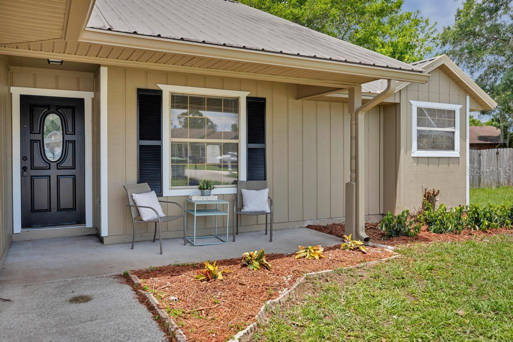 A tan house exterior with a metal roof, a front porch, and a black door — 6109 W 1ST MANOR, PALATKA, FL