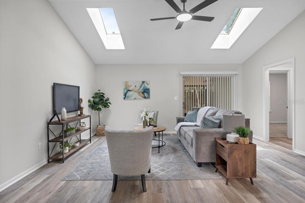 A living room features vaulted ceilings with skylights, a ceiling fan, and wood-look flooring — 6109 W 1ST MANOR, PALATKA, FL