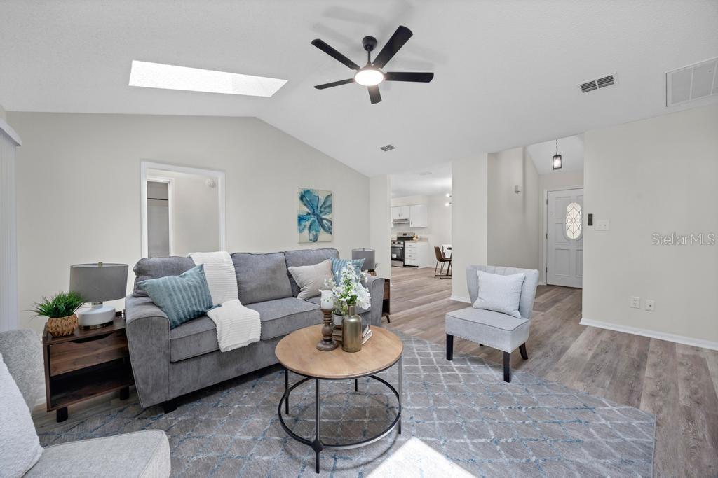 A living room features a grey sofa, a round coffee table, and a vaulted ceiling — 6109 W 1ST MANOR, PALATKA, FL