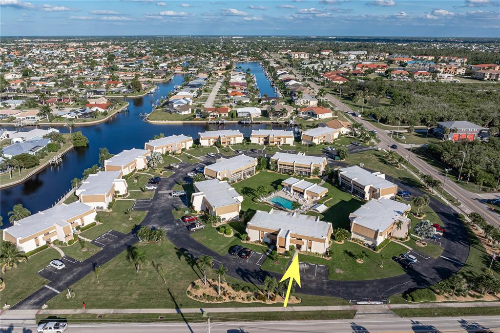 An aerial view shows a multi-unit residential complex with a central pool and parking lots — 1080 BAL HARBOR BOULEVARD UNIT 11B, PUNTA GORDA, FL