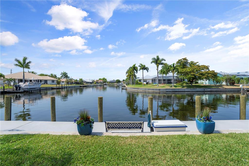 A view of a canal from a grassy backyard with a bench and two planters — 1080 BAL HARBOR BOULEVARD UNIT 11B, PUNTA GORDA, FL