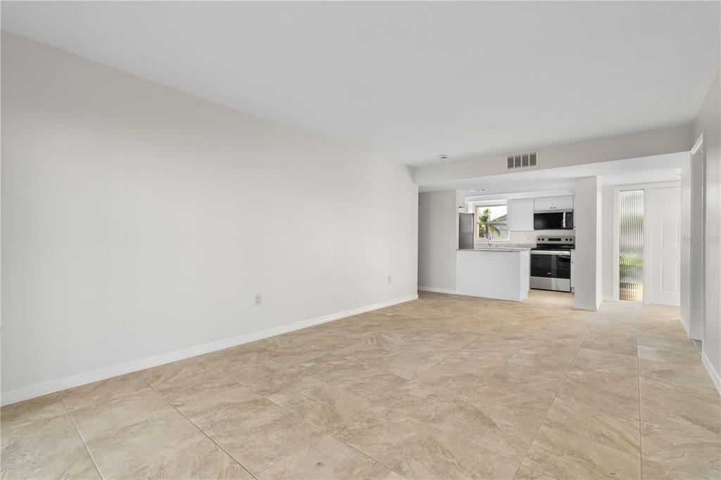 An open-concept living area with light-colored walls and large, neutral-toned floor tiles — 1080 BAL HARBOR BOULEVARD UNIT 11B, PUNTA GORDA, FL