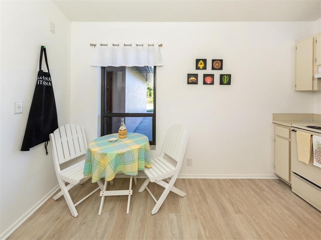 A dining area features a small table with two white chairs, a window, and artwork — 401 CURRY STREET UNIT 66, NOKOMIS, FL