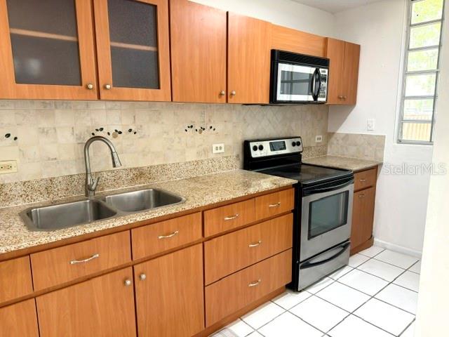 A kitchen features wood cabinets, granite countertops, stainless steel appliances, and a tiled backsplash — 5870 JOSE TARTAK STREET UNIT B1, CAROLINA, PR