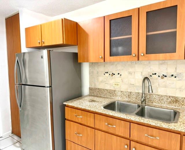 A kitchen features light wood cabinets, a stainless steel refrigerator, and a double-basin sink — 5870 JOSE TARTAK STREET UNIT B1, CAROLINA, PR