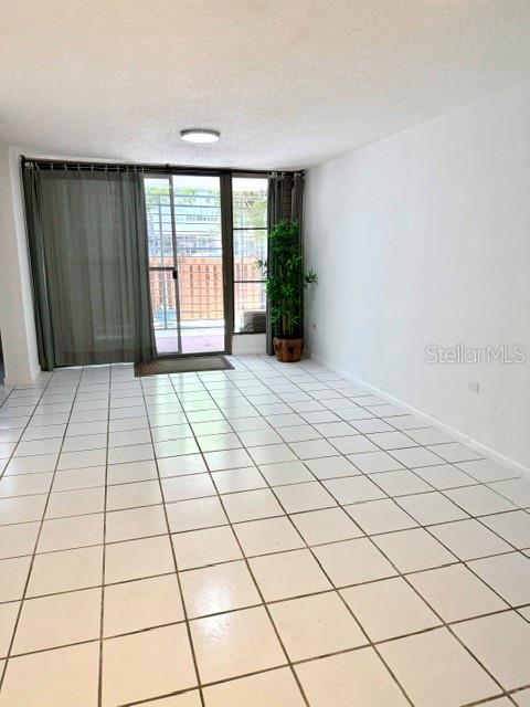 A living room features white tile flooring, a sliding glass door, and a potted plant — 5870 JOSE TARTAK STREET UNIT B1, CAROLINA, PR