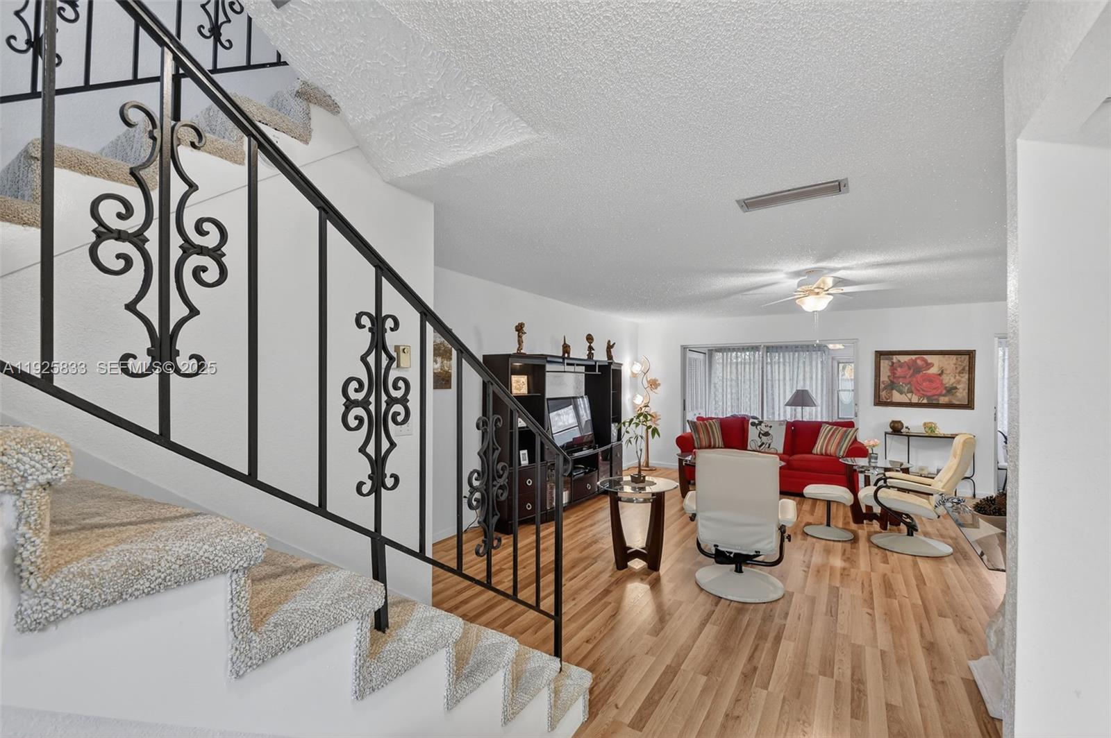 A living room with wood-look flooring features a staircase with a decorative black metal railing — 820 Salem Ln # B, Lake Worth FL 33467, LAKE WORTH, FL