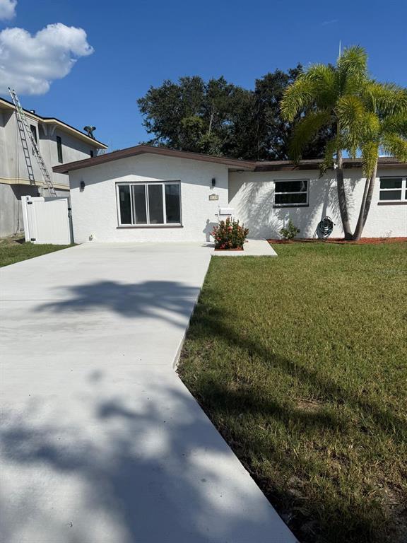 A white single-story house with a concrete driveway and a palm tree in the yard — 4119 HARRISBURG STREET NE, ST PETERSBURG, FL