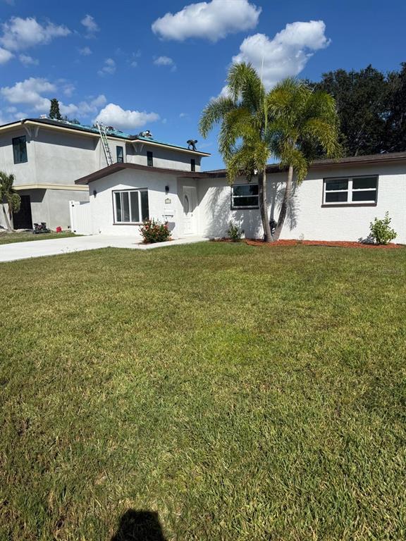 A white, single-story house with a palm tree and a neighboring two-story building — 4119 HARRISBURG STREET NE, ST PETERSBURG, FL