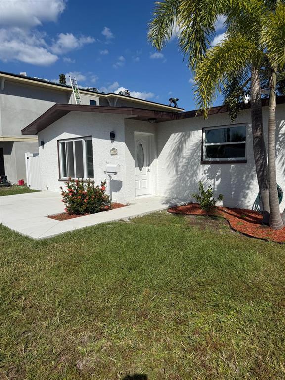 A white stucco house exterior features a front door, a large window, and a palm tree — 4119 HARRISBURG STREET NE, ST PETERSBURG, FL