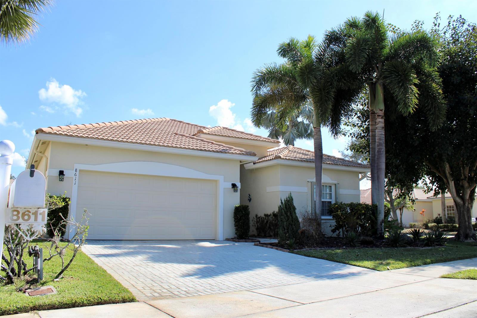A single-story house with a beige stucco exterior, tile roof, and a paved driveway — 8611 Gold Cay, West Palm Beach FL 33411, WEST PALM BEACH, FL