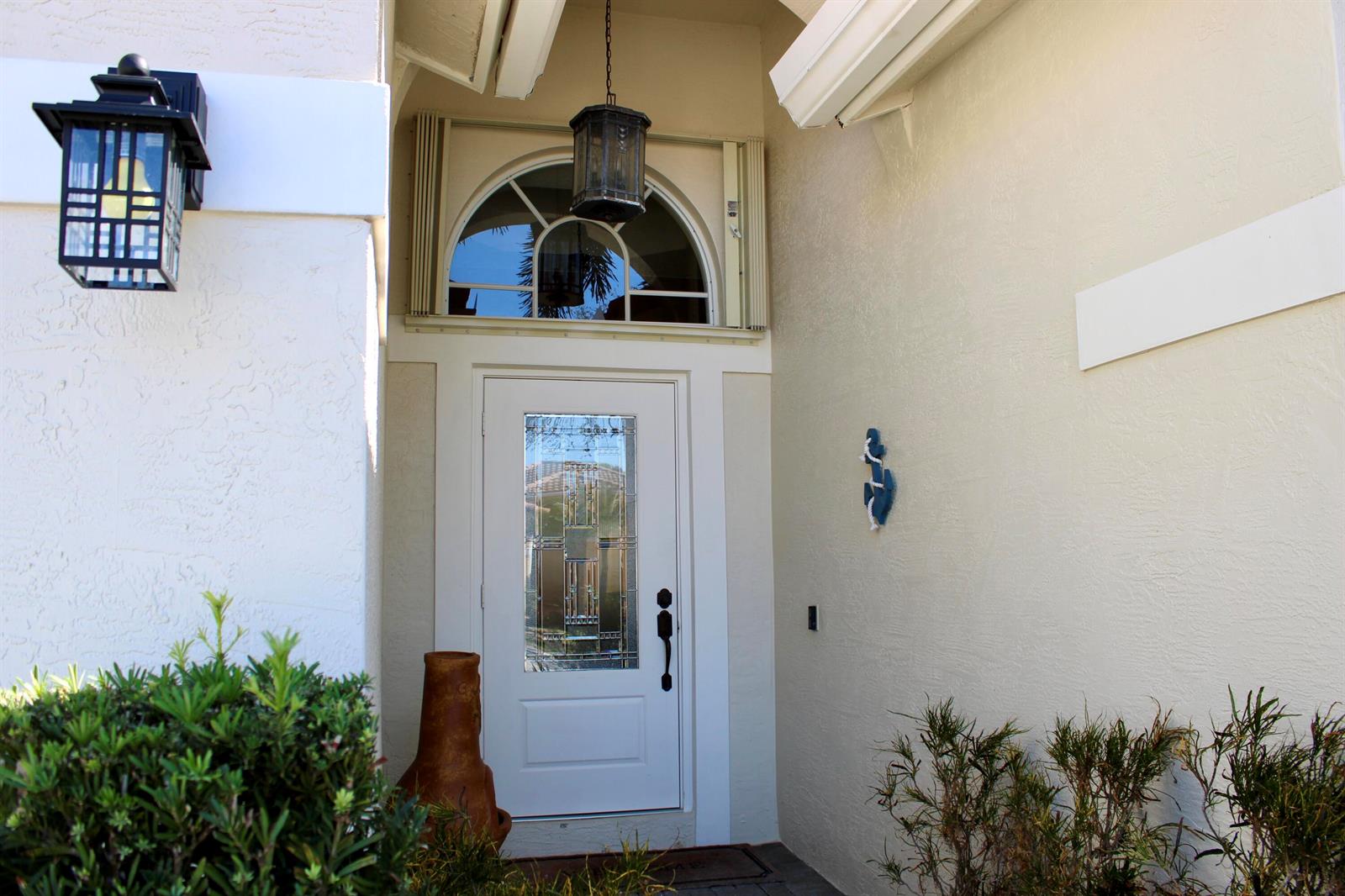 The front entrance features a white door with a glass insert and an arched transom window — 8611 Gold Cay, West Palm Beach FL 33411, WEST PALM BEACH, FL