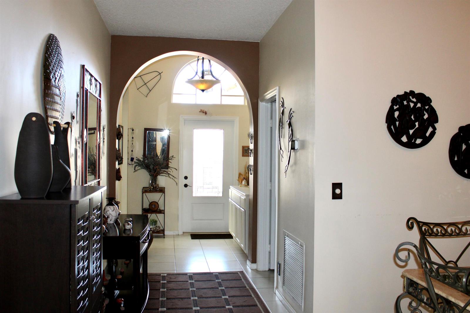 A foyer features a large arched entryway, tile flooring, and a white front door — 8611 Gold Cay, West Palm Beach FL 33411, WEST PALM BEACH, FL