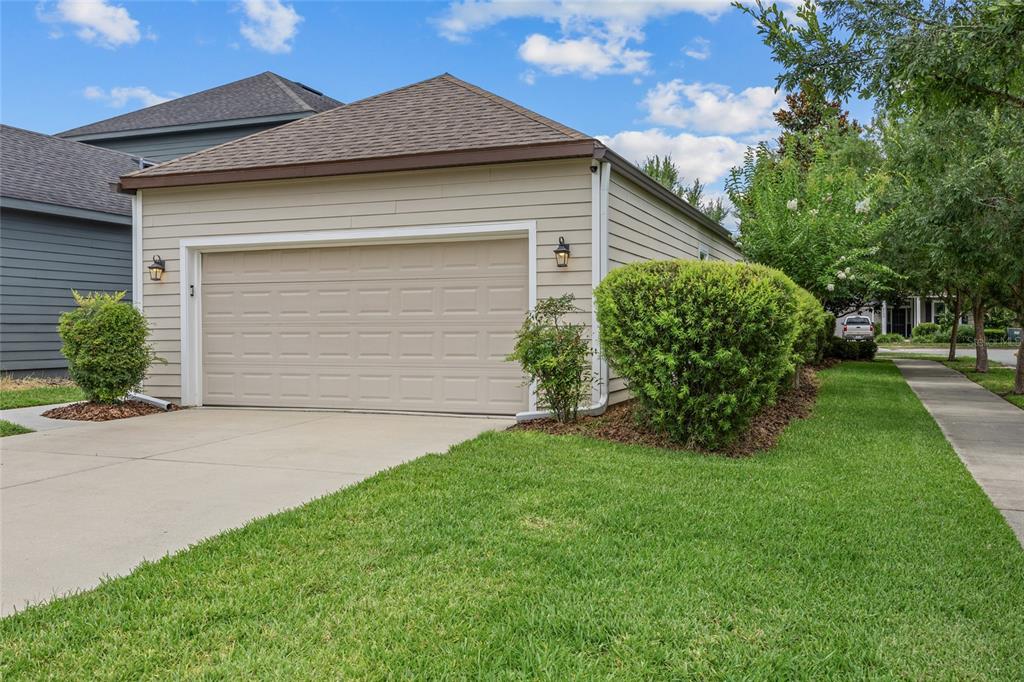A detached garage with beige horizontal siding and a tan sectional door sits on a lawn — 8251 SW 78TH LANE, GAINESVILLE, FL
