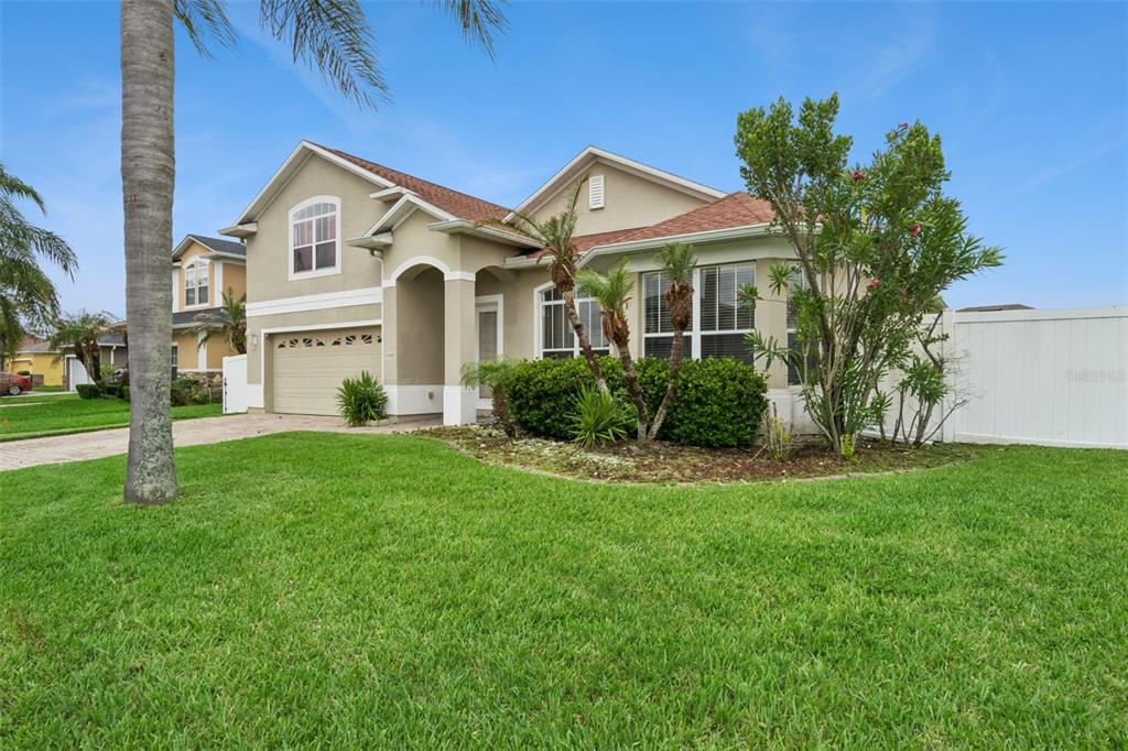 A two-story suburban house with a tan exterior, a two-car garage, and a palm tree — 1900 ACACIA DRIVE, KISSIMMEE, FL