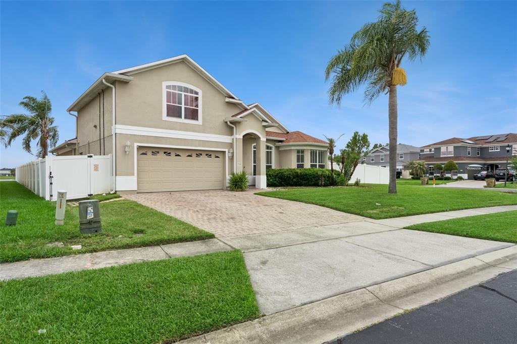A two-story suburban house with a tan stucco exterior, a two-car garage, and a lawn — 1900 ACACIA DRIVE, KISSIMMEE, FL
