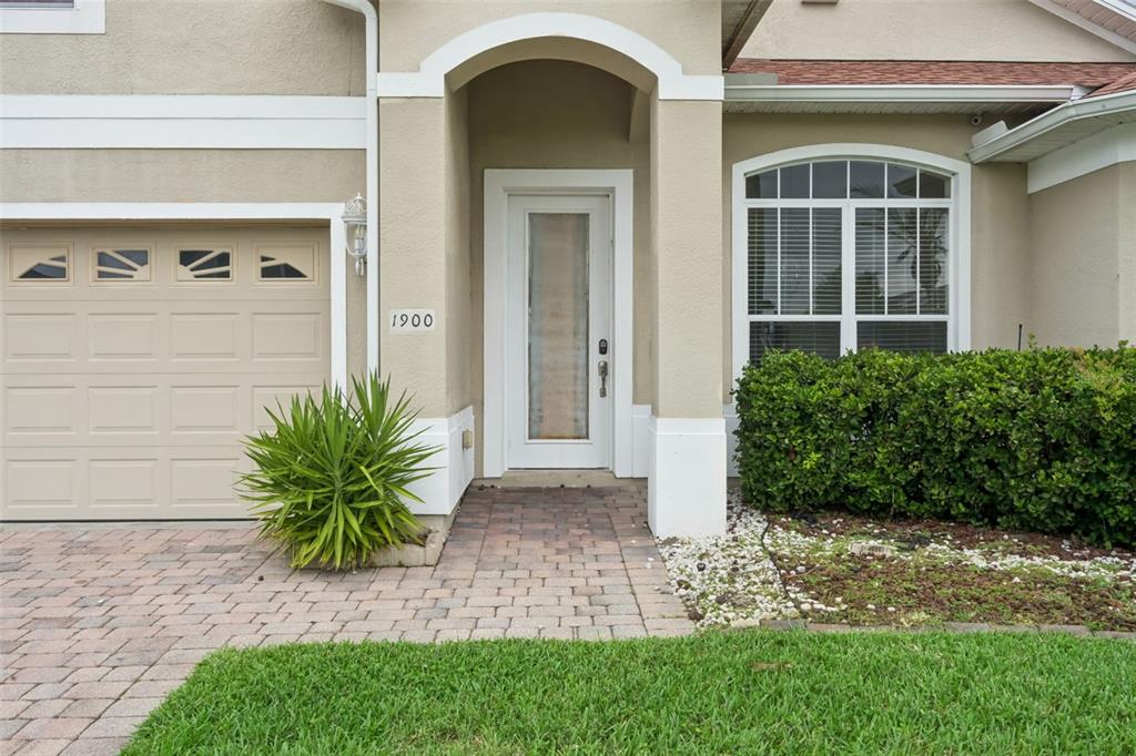 A two-story suburban house with a tan exterior, a paved driveway, and a palm tree — 1900 ACACIA DRIVE, KISSIMMEE, FL