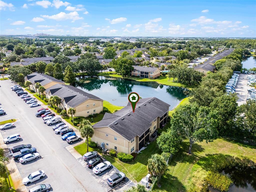 An aerial view shows a multi-story apartment building situated next to a pond and parking — 2401 BARLEY CLUB COURT UNIT 2, ORLANDO, FL