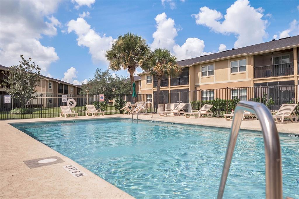 A swimming pool with lounge chairs sits in front of a multi-story apartment building — 2401 BARLEY CLUB COURT UNIT 2, ORLANDO, FL