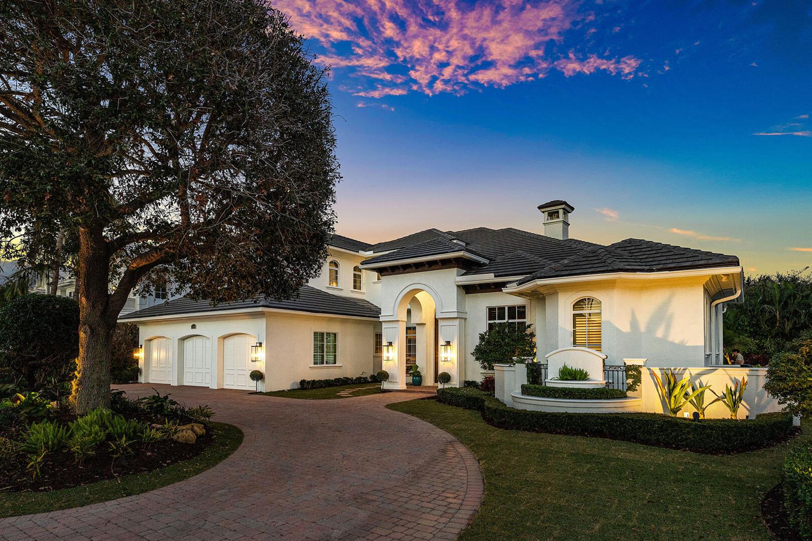 A white stucco house with a three-car garage and a curved brick driveway at dusk — 2310 W Silver Palm Road, Boca Raton FL 33432, BOCA RATON, FL