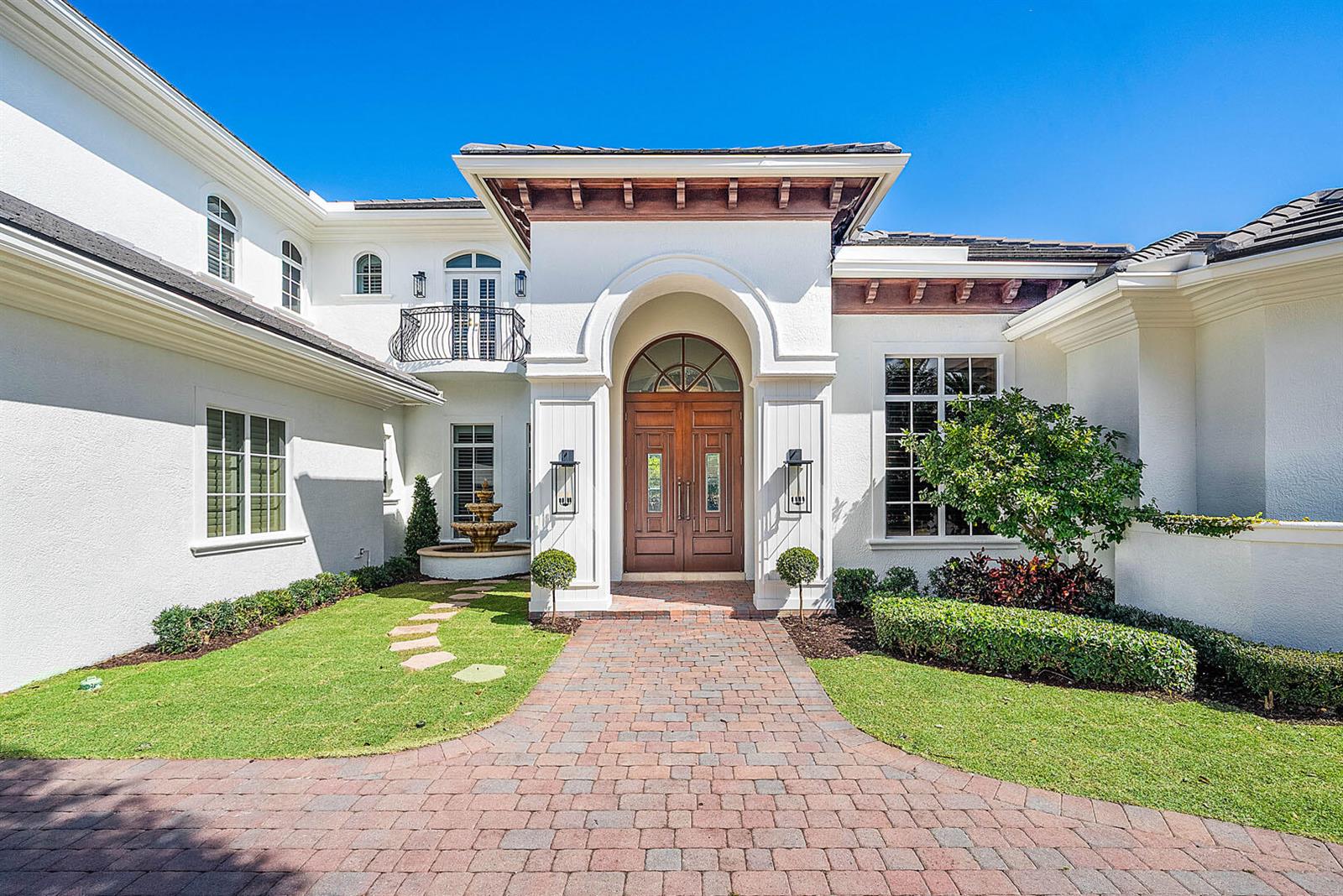A white stucco house features a brick walkway leading to a large arched wooden door — 2310 W Silver Palm Road, Boca Raton FL 33432, BOCA RATON, FL