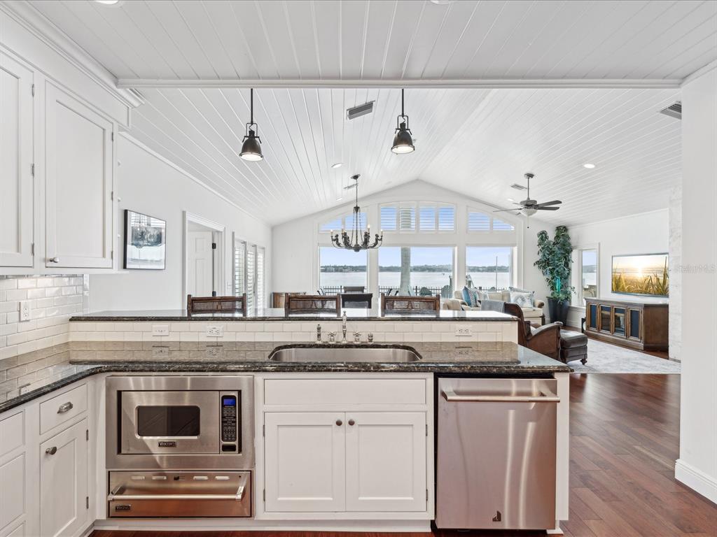 A kitchen with white cabinets and stainless steel appliances overlooks a living area and water — 450 22ND STREET, BELLEAIR BEACH, FL